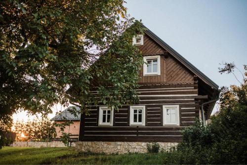 a wooden house with white windows and a tree at Bohdašín 17 in Červený Kostelec