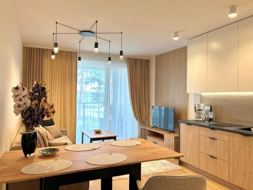 a kitchen and living room with a wooden table and a dining room at Apartamenty Bryza nad jeziorem in Augustów