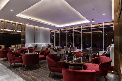 a restaurant with red chairs and tables and windows at Ramada by Wyndham Riyadh King Fahd Road in Riyadh
