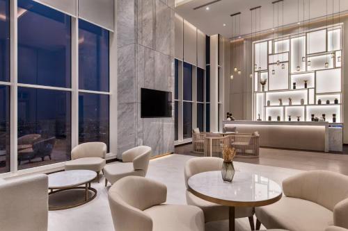 a lobby with chairs and tables and a television at Ramada by Wyndham Riyadh King Fahd Road in Riyadh