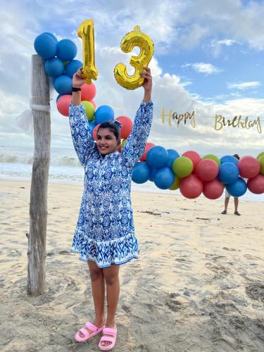 a young girl holding balloons with a happy birthday sign at Marari Beach Villas in Mararikulam