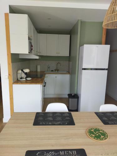 une cuisine avec une table et un réfrigérateur blanc dans l'établissement marie, à Anglet