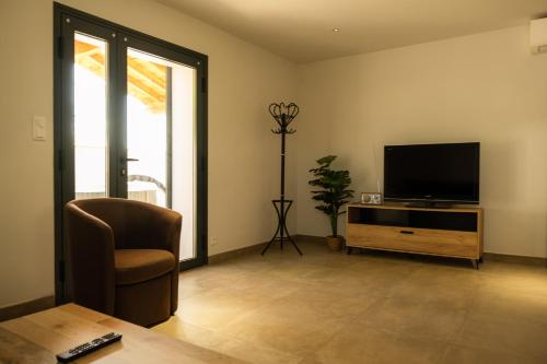 a living room with a television and a chair at Domaine Saint Thomas in Argelès-sur-Mer