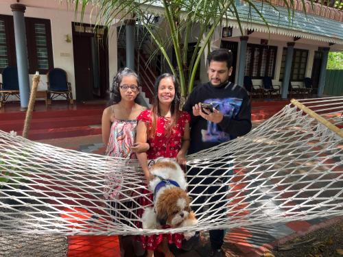 a man taking a picture of two women and a dog in a hammock at Marari Beach Villas in Mararikulam