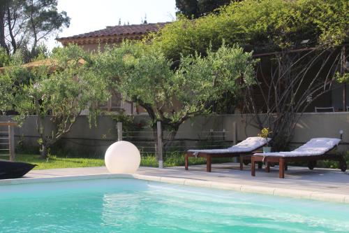 une piscine avec deux chaises et une table à côté dans l'établissement Mas Eva, à Mouriès
