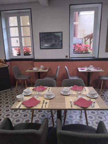 a dining room with a table and chairs and windows at Hotel Le Normandy in Beaumont-de-Lomagne