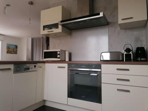 une cuisine avec des armoires blanches et un four à plaques de cuisson dans l'établissement T3 avec extérieur Sanary centre, à Sanary-sur-Mer