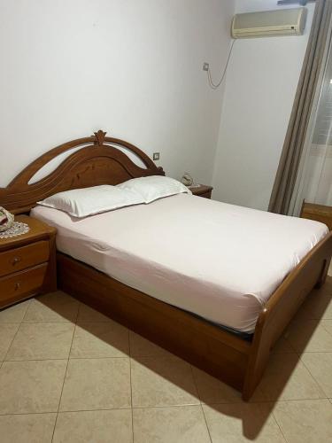 a bed with a wooden headboard in a bedroom at Nori House in Vlorë