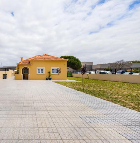 a yellow house with a brick driveway at Pontes Guest House in Arcozelo