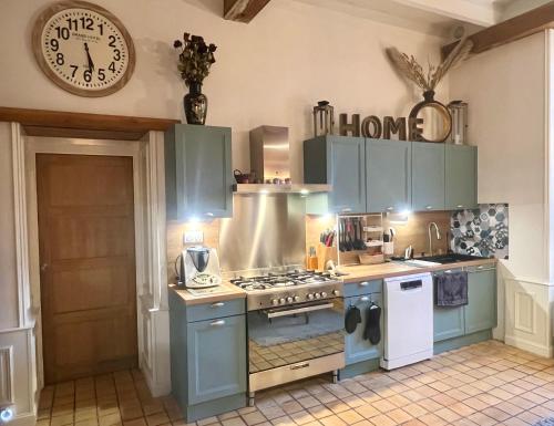 une cuisine avec des placards bleus et une horloge murale dans l'établissement Chambres d'hôtes Les Carmélites, à Guingamp