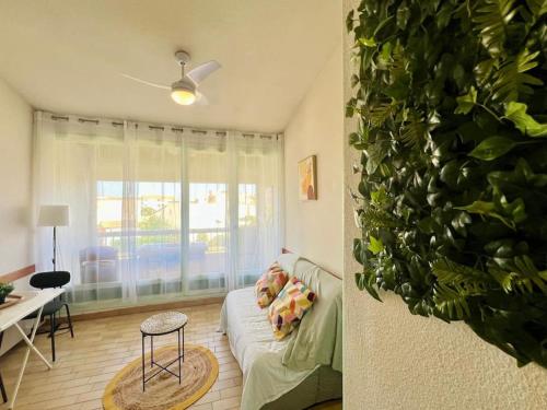 un salon avec un canapé et une plante dans l'établissement L'Olive du Cap, au Cap d'Agde