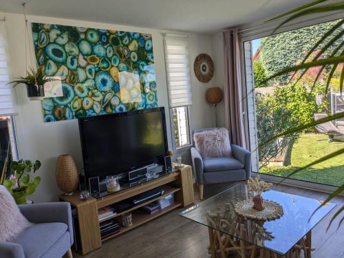 un salon avec une télévision à écran plat et une table dans l'établissement Maison de pêcheur à 150 m de la mer avec jacuzzi, à Ouistreham