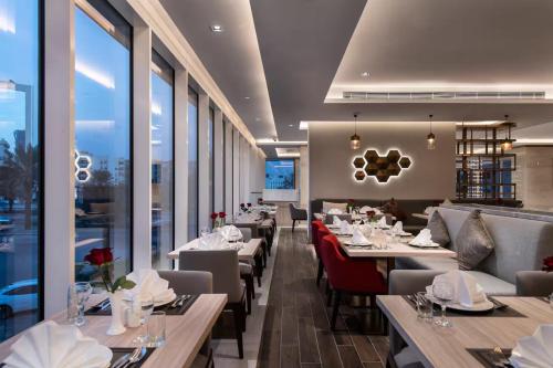 a restaurant with tables and chairs and windows at Ramada by Wyndham Riyadh King Fahd Road in Riyadh