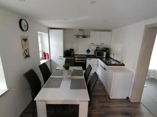 a kitchen with a white table and chairs in a room at Ferienwohnung in Mittelsaida in Großhartmannsdorf