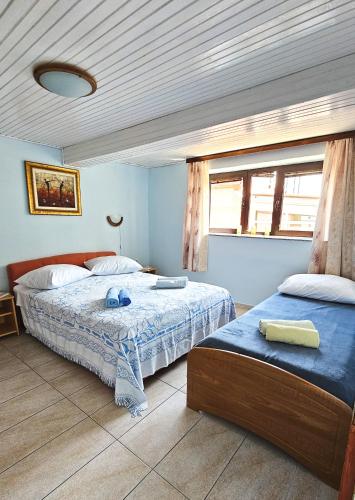 a bedroom with two beds and a window at Apartmani Mediteran in Vrh