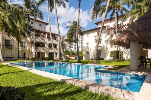 a swimming pool in front of a building with palm trees at Stunning condo in excellent location in Cancún