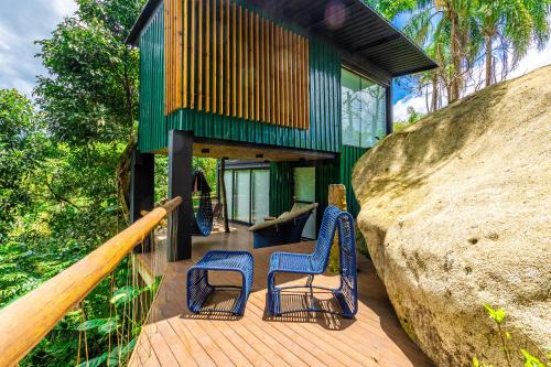 a house with two blue chairs on a wooden deck at Casa Natu Ilhabela Portinho in Ilhabela