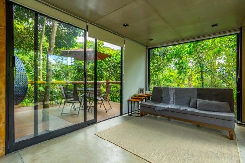 a living room with a couch and glass doors at Casa Natu Ilhabela Portinho in Ilhabela