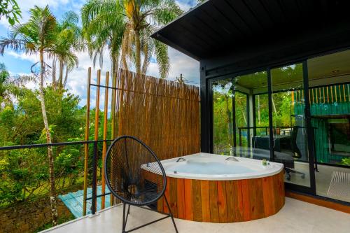 a bath tub sitting on a balcony next to a house at Casa Natu Ilhabela Portinho in Ilhabela