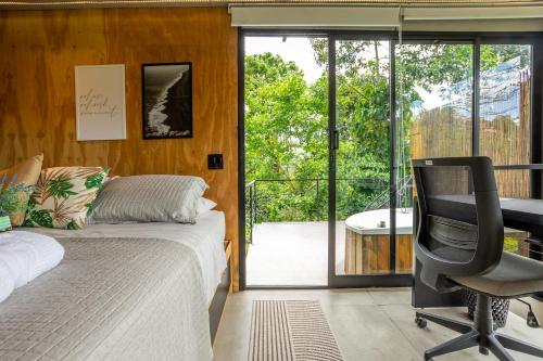 a bedroom with a bed and a desk and a chair at Casa Natu Ilhabela Portinho in Ilhabela