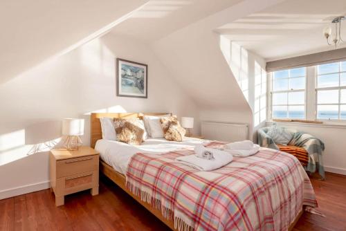 a bedroom with a bed with a plaid blanket at Shore House - Pittenweem in Pittenweem