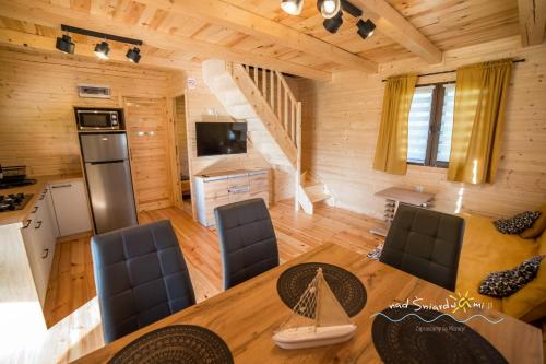 a living room with a dining room table in a log cabin at Domki Letniskowe NAD ŚNIARDWAMI BARBARA MAJKRZAK in Nowe Guty