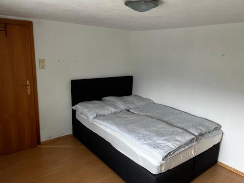 a bed in a room with a white wall at Unterkunft LUSCHIN in Spielberg