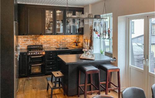 a kitchen with black cabinets and a island with bar stools at 2 Bedroom Nice Home In Ystad in Ystad