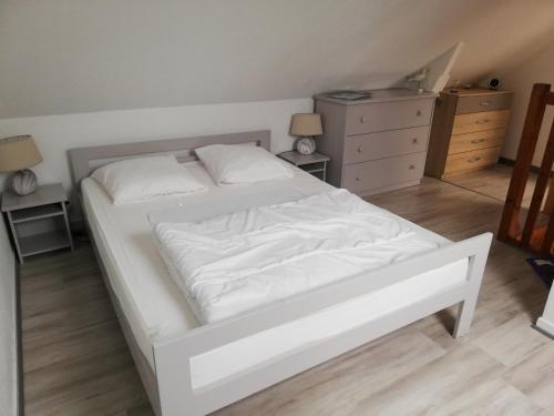 une chambre avec un lit blanc et une commode dans l'établissement GITE pour 4 personnes - proche des plages et GR 34, à Clohars-Carnoët