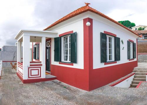 une petite maison rouge et blanche avec des volets verts dans l'établissement Renovated Traditional House w 3BR & Outdoor Space, à Funchal