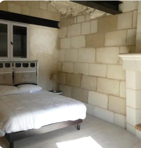 une chambre avec un lit et un mur de briques dans l'établissement Troglo Saumurois, à Chacé