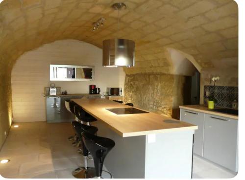 une cuisine avec un comptoir et des tabourets dans une pièce dans l'établissement Troglo Saumurois, à Chacé