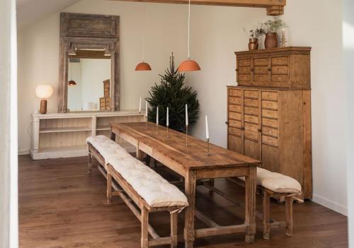 une salle à manger avec une table en bois avec des bancs et un miroir dans l'établissement Les Biches, Maison Familiale jusqu'à 10 personnes, à Noyers-sur-Cher