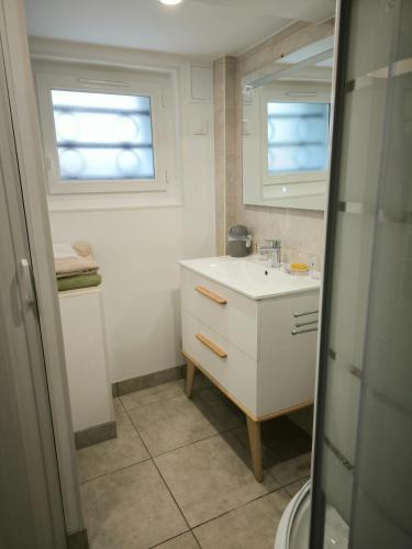La salle de bains est pourvue d'un lavabo blanc et de 2 fenêtres. dans l'établissement Chez nous chez vous, à Vaires-sur-Marne