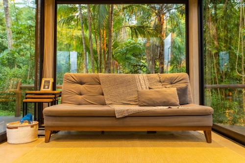 a couch in a room with a large window at Casa Natu Ilhabela Portinho in Ilhabela