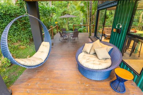 a porch with two swinging chairs and a table at Casa Natu Ilhabela Portinho in Ilhabela