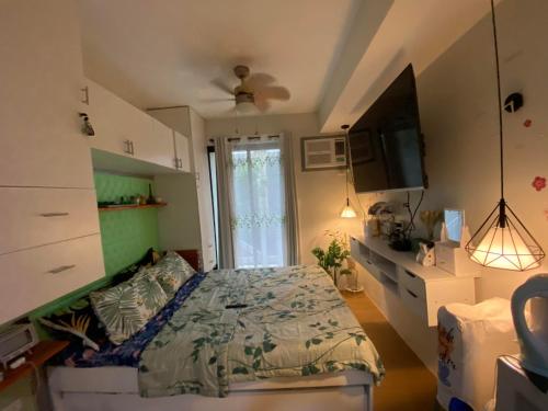 a bedroom with a bed and a tv and a window at Summer10th Pinesuites Scandi Minimalist Deluxe in Tagaytay