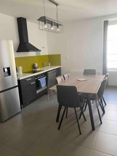 une cuisine avec une table, des chaises et un réfrigérateur dans l'établissement L'appartement des tortues, à Châteaubriant