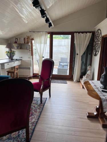 un salon avec une chaise rouge et une table dans l'établissement Cottage Apolline, à Santenay