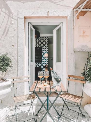 a table and chairs on a patio with wine glasses at CerezinoFlats- Blue Bay Studio in Seixal