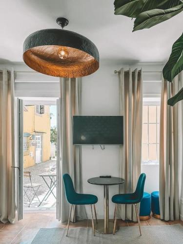 a dining room with a table and chairs and a chandelier at CerezinoFlats- Blue Bay Studio in Seixal