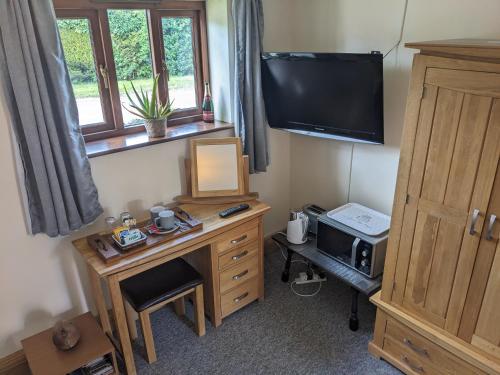 a room with a desk with a television and a deskictericter at South Barn in Stanningfield