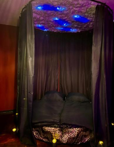 a bed in a tent with a purple ceiling at Suite mit Whirlpool, Sauna, Pole Dance und mehr in Essen