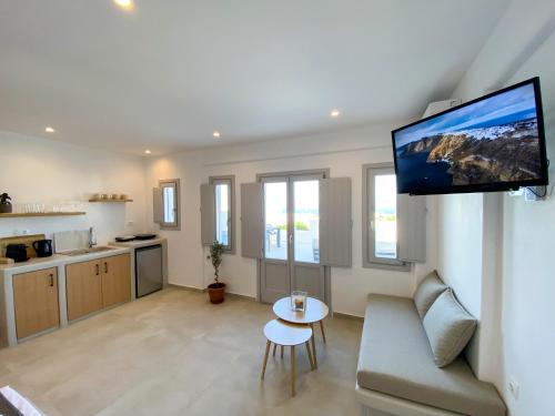 a living room with a couch and a tv on a wall at Nohēme Luxury Suites in Vourvoulos