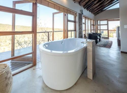 a large bath tub in a room with a large window at Des'lgodini Lodge - PRM078 in Bela-Bela