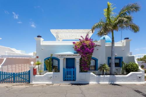 a white house with a palm tree and flowers at KATIS Villas Fuerteventura in Corralejo