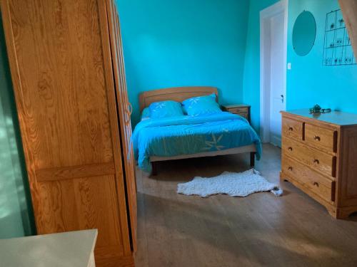 - une chambre bleue avec un lit et une commode dans l'établissement Chez Gigi, à Huchenneville