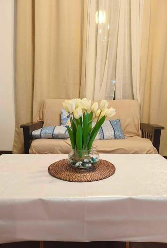 a vase of flowers on a table with a couch at Rustic Log Cabin in Tagaytay in Tagaytay