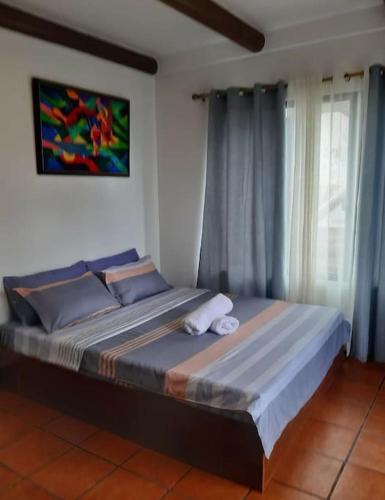 a large bed in a bedroom with blue curtains at Rustic Log Cabin in Tagaytay in Tagaytay