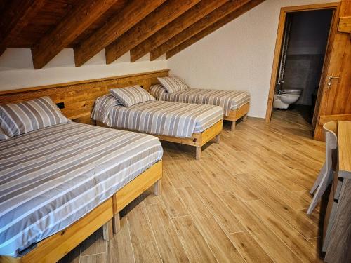 two beds in a room with wooden floors at La Genzianella affittacamere in Santo Stefano dʼAveto